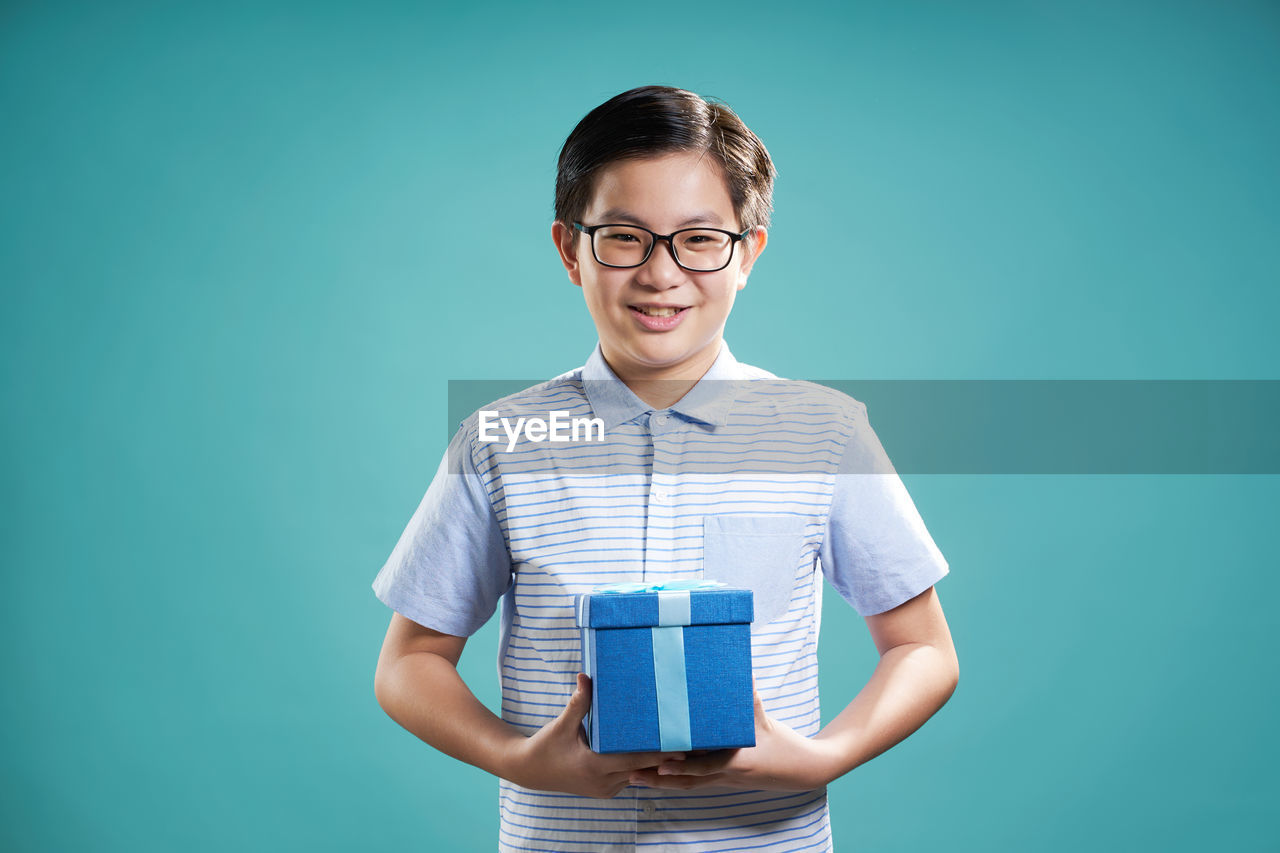 Close-up of boy holding gift against blue background