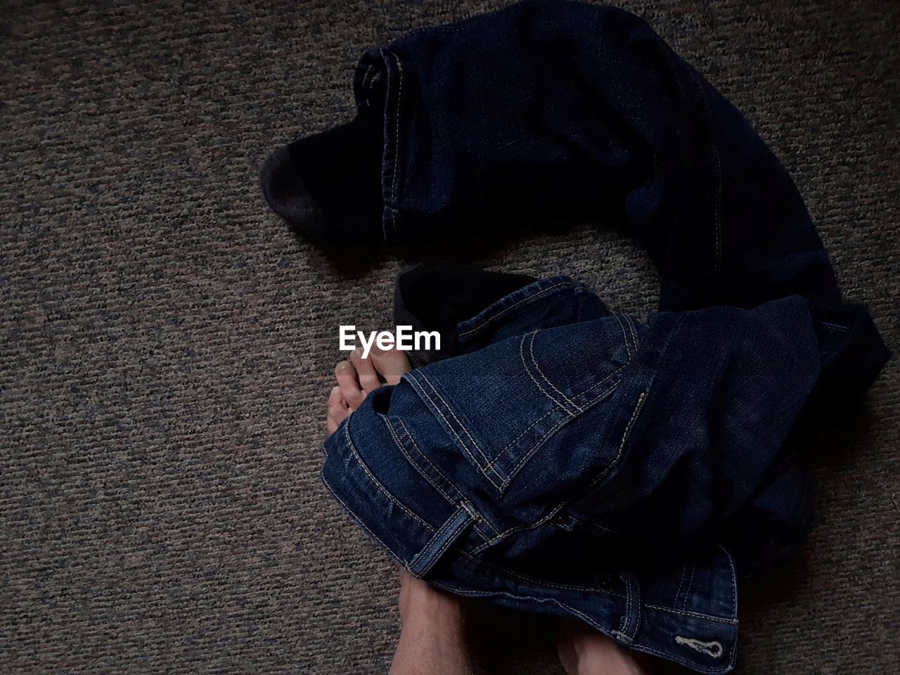 Low section of person with jeans on carpet