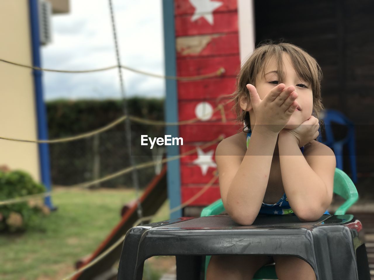 Girl looking away while sitting on chair at backyard