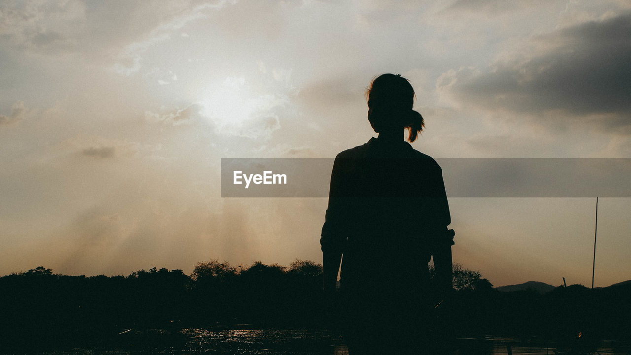 Silhouette girl standing against sky during sunset