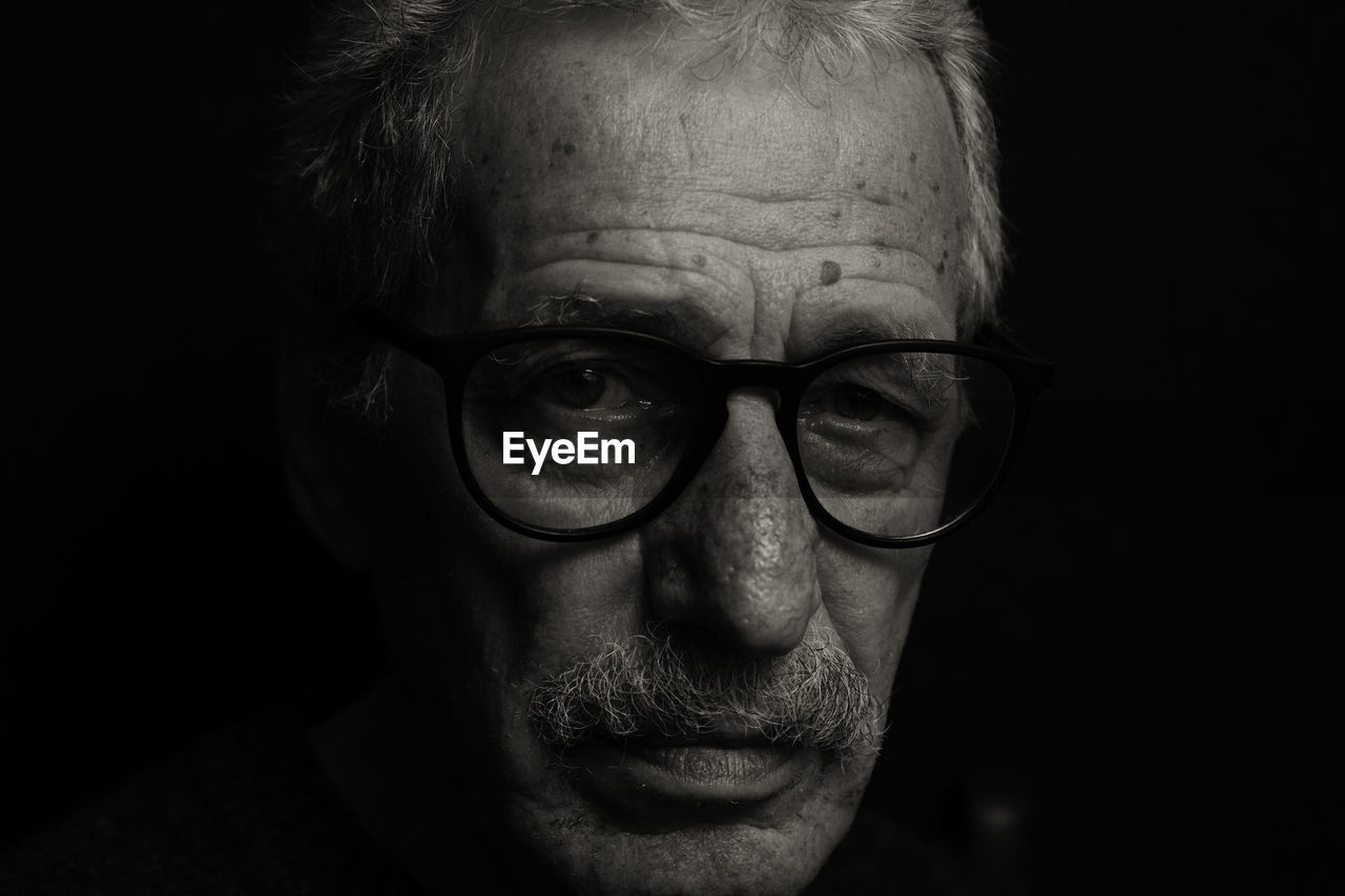 Portrait of man wearing eyeglasses in darkroom