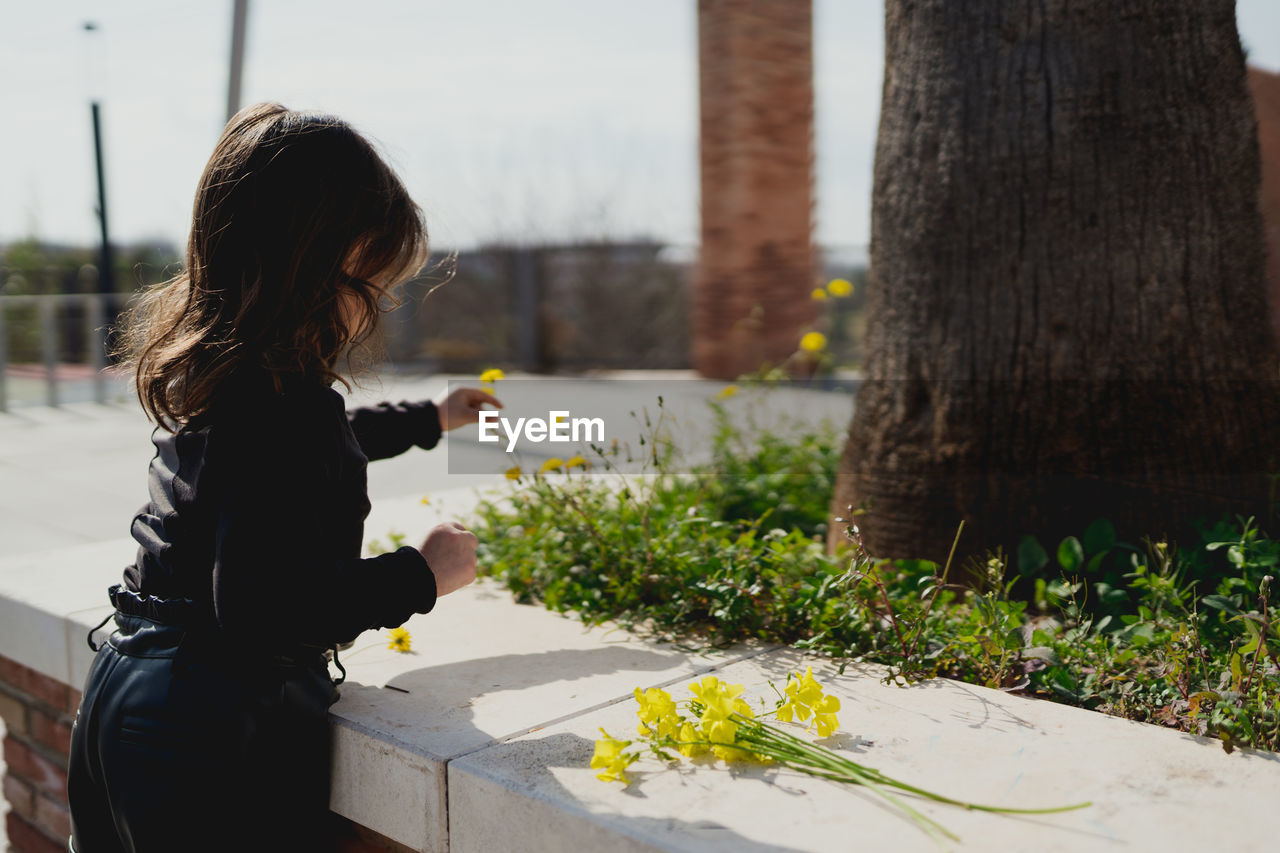 Adorable four-year-old girl looking at the yellow flowers in her hand