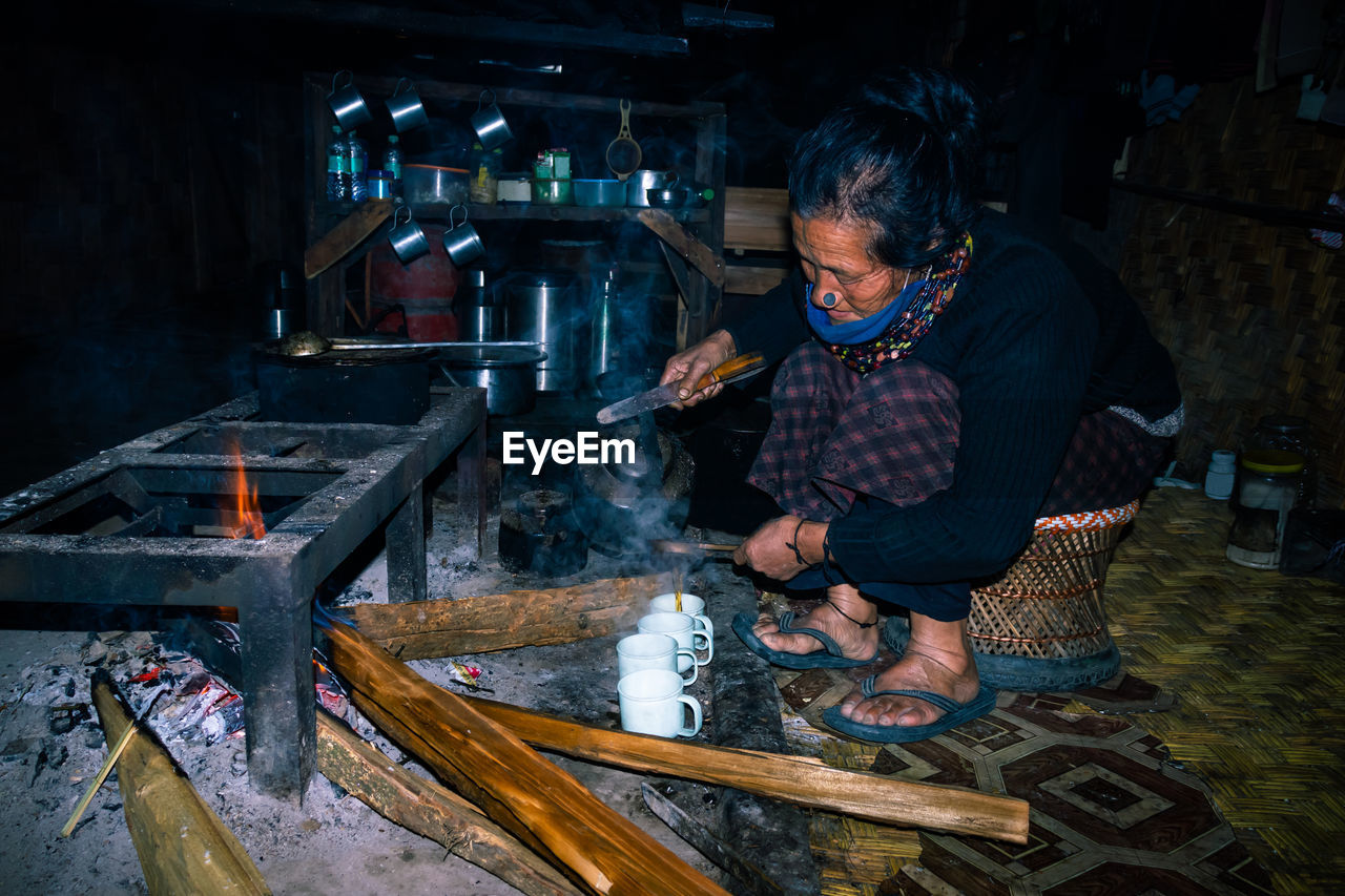 Apatani tribal lady making tea at her home near fire place at evening