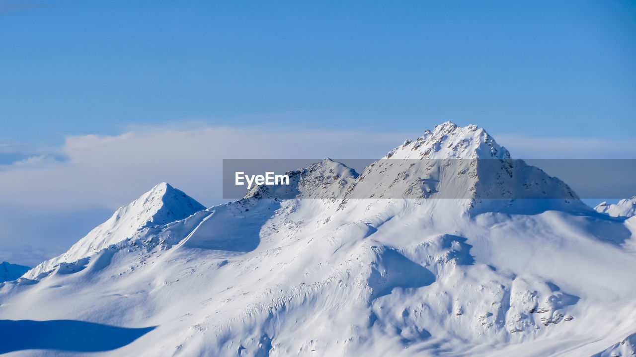 Snowy mountain peaks against the blue sky and clouds. a beautiful winter mountain landscape