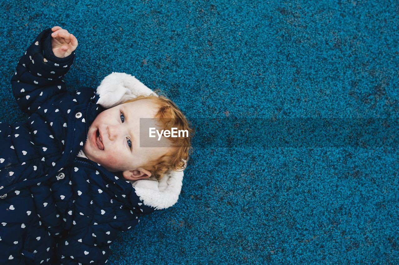 HIGH ANGLE PORTRAIT OF CUTE BABY LYING ON BLUE EYES