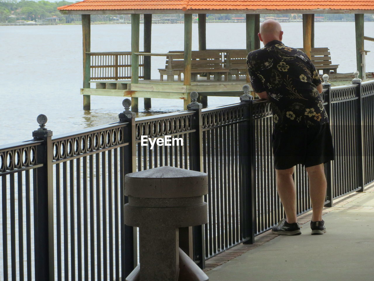 Rear view of man standing by railing over river
