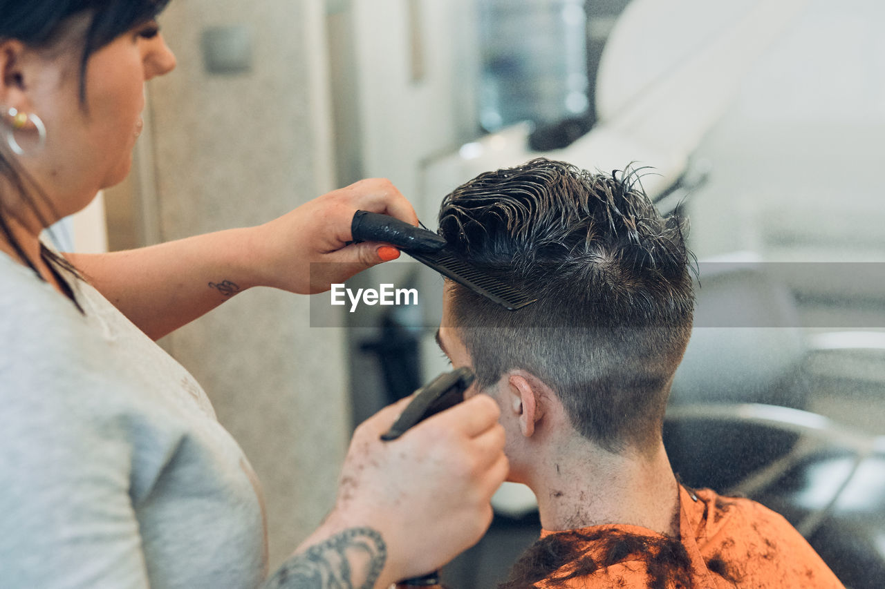 Woman cutting man hair in salon