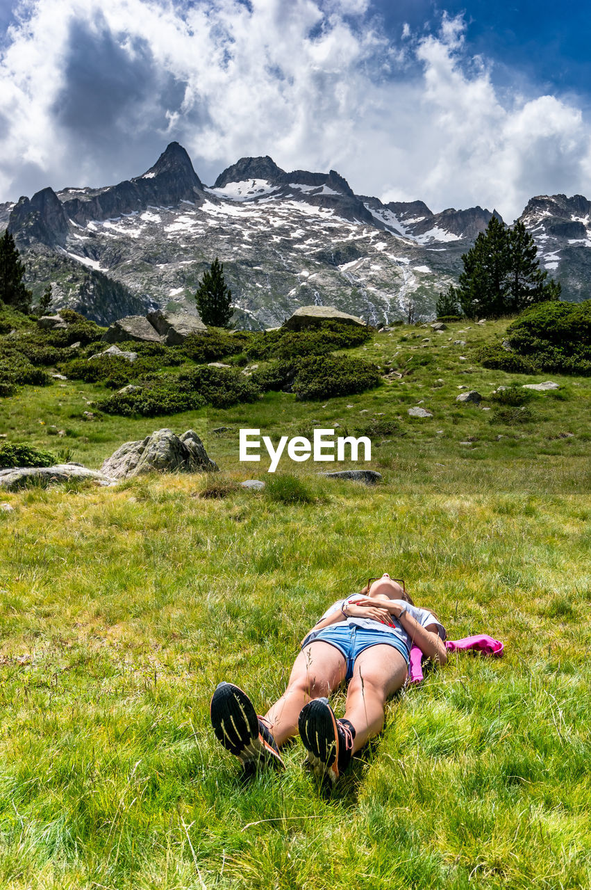 Woman lying down on field against mountains