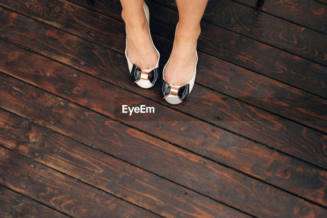 Low section of woman standing on wooden floor