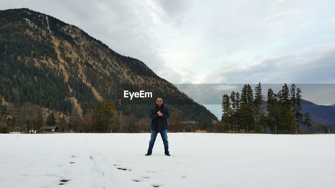 Full length portrait of man standing on snowfield against mountain