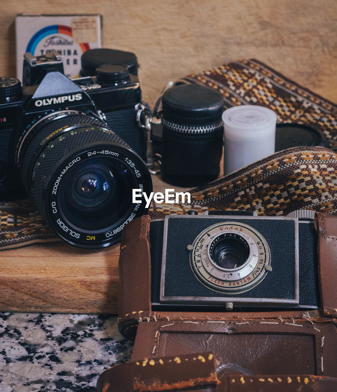 camera, technology, lens - optical instrument, retro styled, photographic equipment, camera lens, digital slr, indoors, no people, still life, lens - eye, nostalgia, camera film, table, arts culture and entertainment, wood, history, the past, photographing, lens, close-up, brown