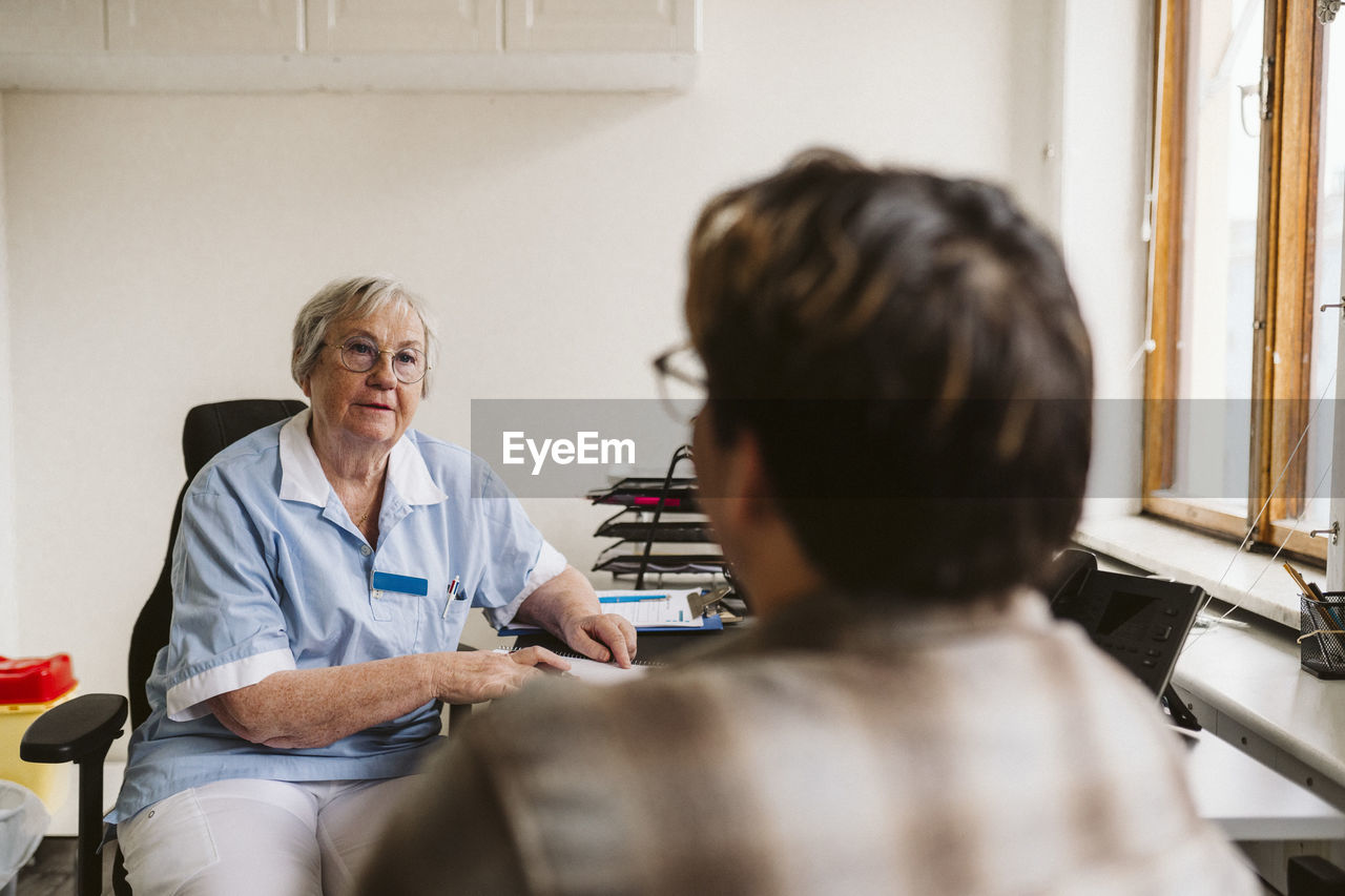 Senior female doctor consulting male patient at medical clinic