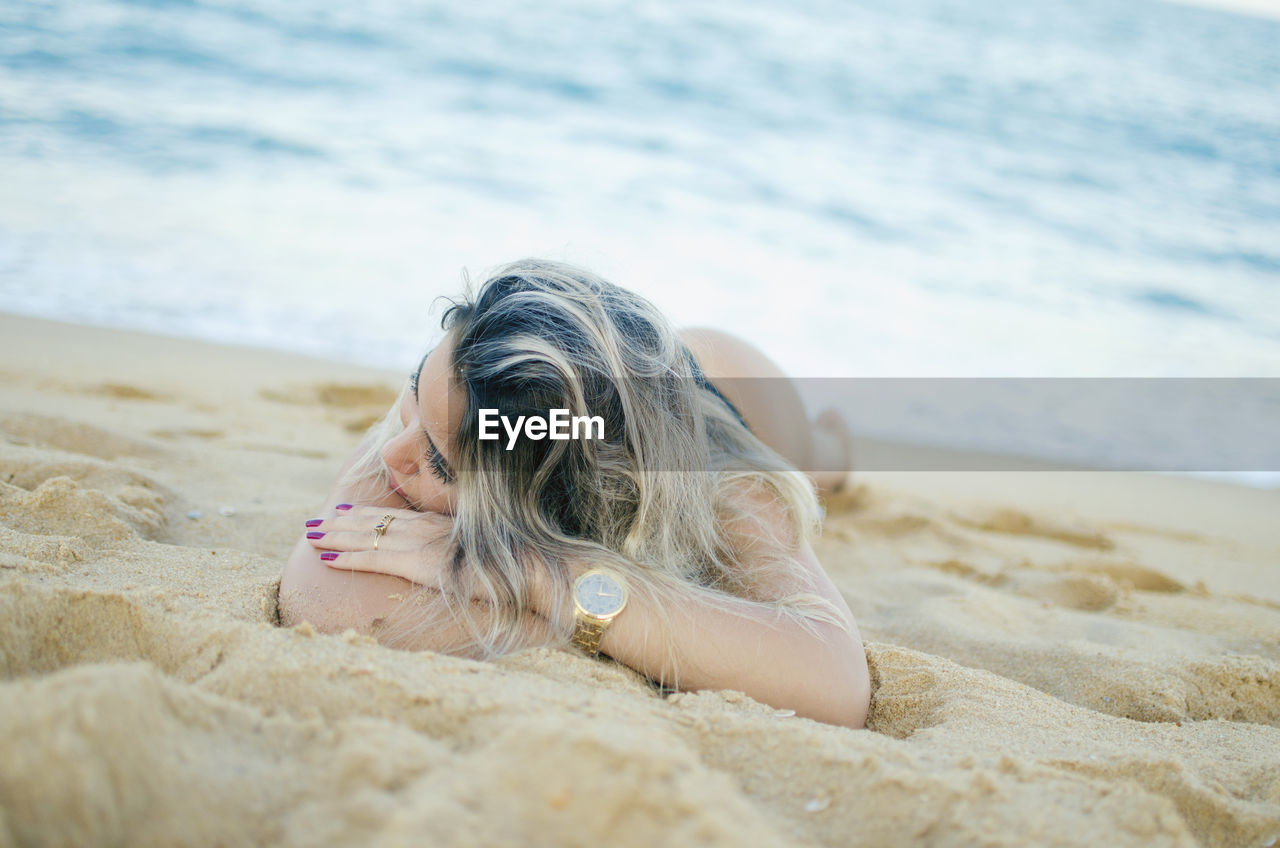 Woman lying down on sand at beach