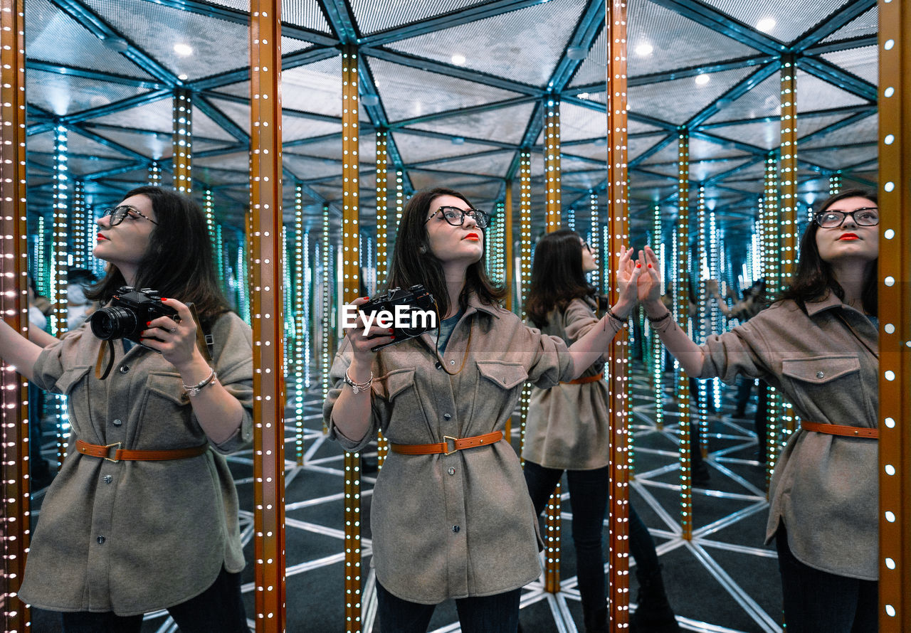 Young woman with camera in mirror maze