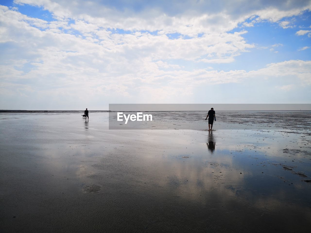 PEOPLE STANDING ON BEACH AGAINST SEA