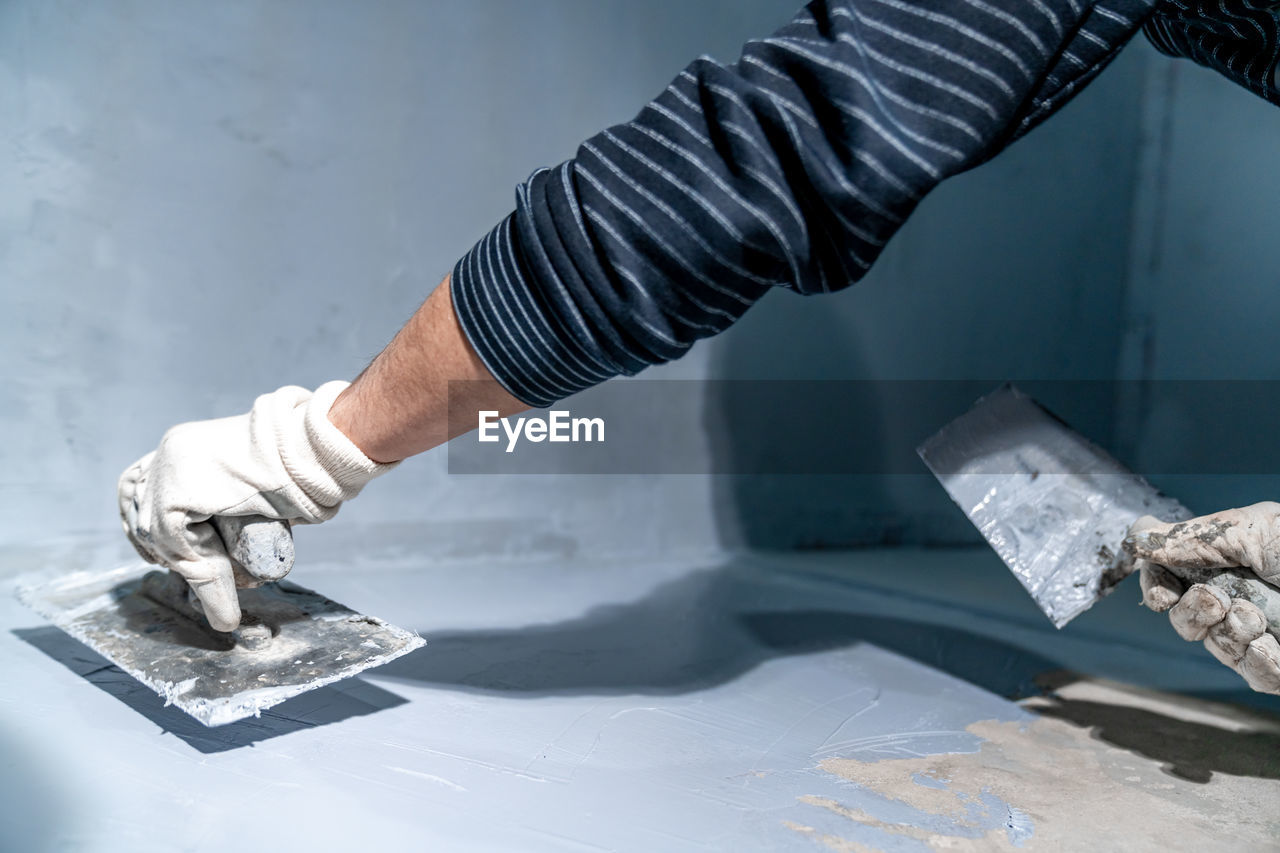 cropped hand of man cutting tile