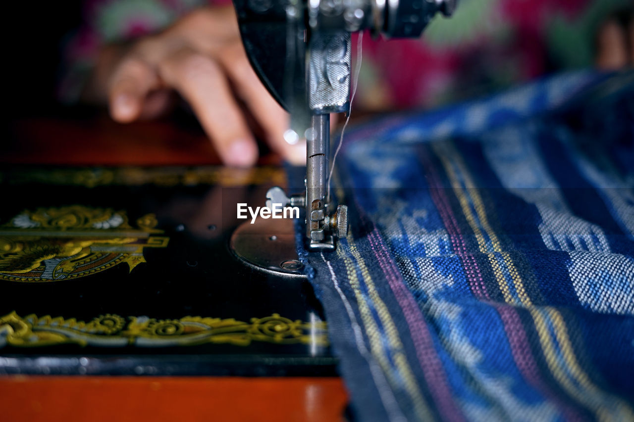 Cropped image of woman using sewing machine