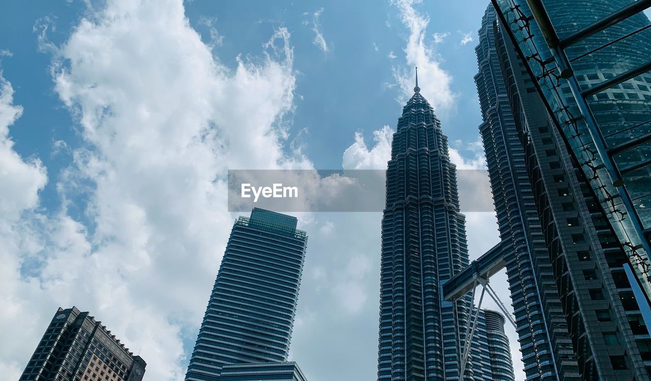 low angle view of skyscrapers against cloudy sky