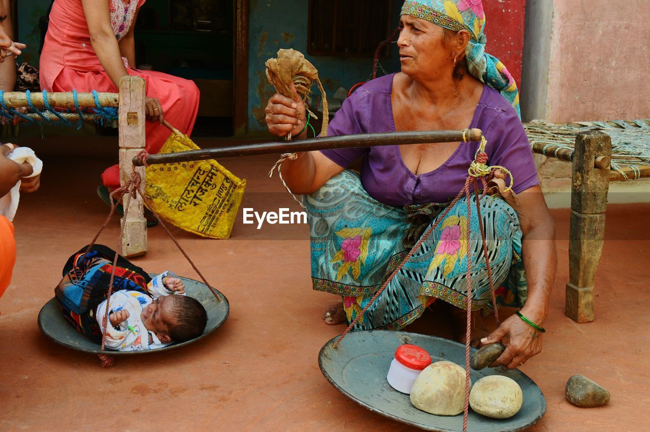 Senior woman measuring baby girl on weight scale