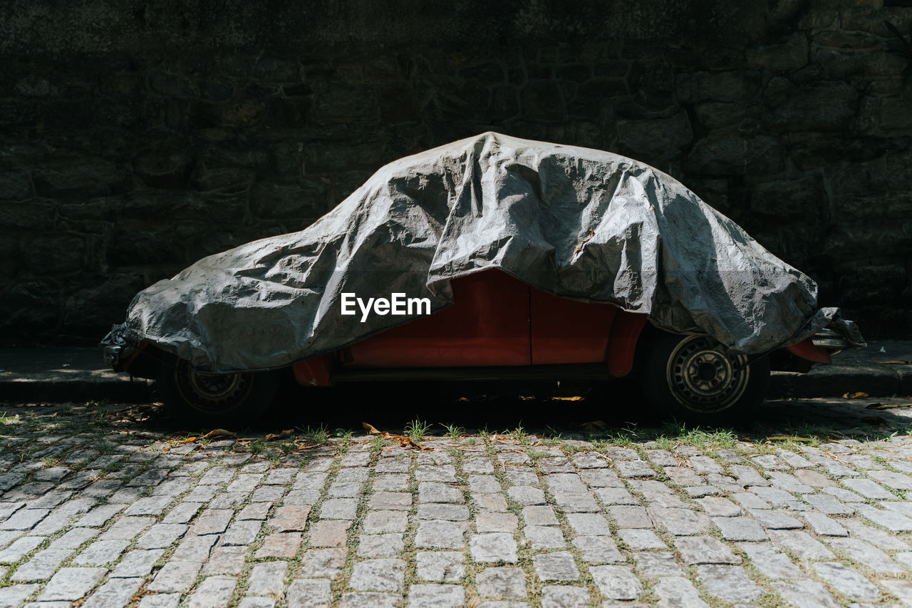 Car with cover on cobblestone street