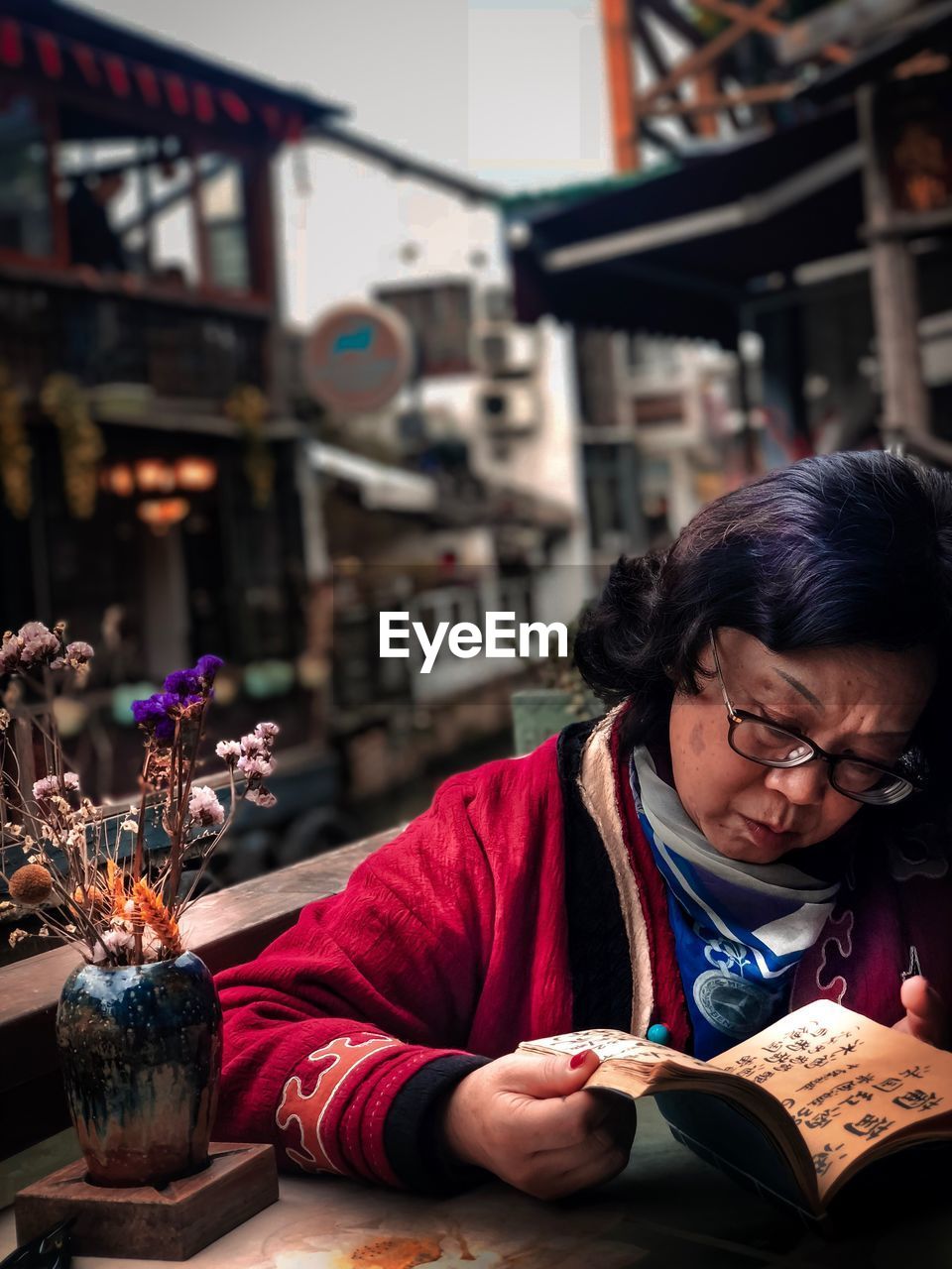 Woman reading book at cafe in city