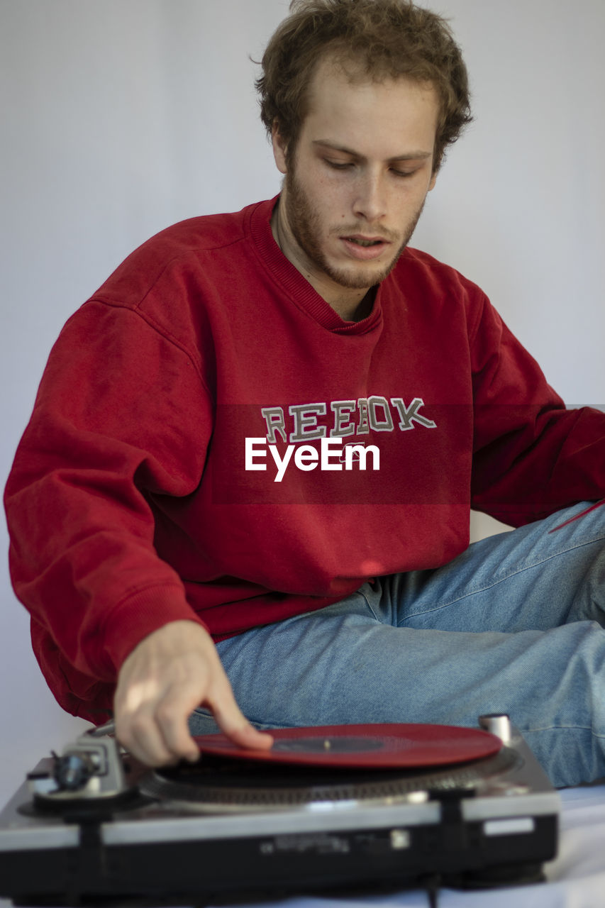 YOUNG MAN LOOKING AWAY WHILE SITTING ON STAGE