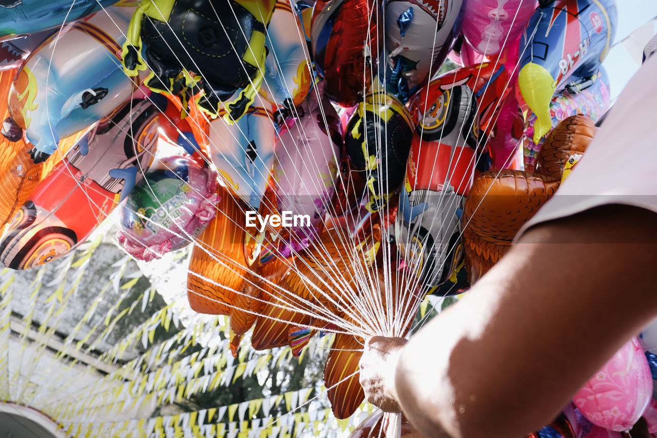 Cropped image of seller holding balloons