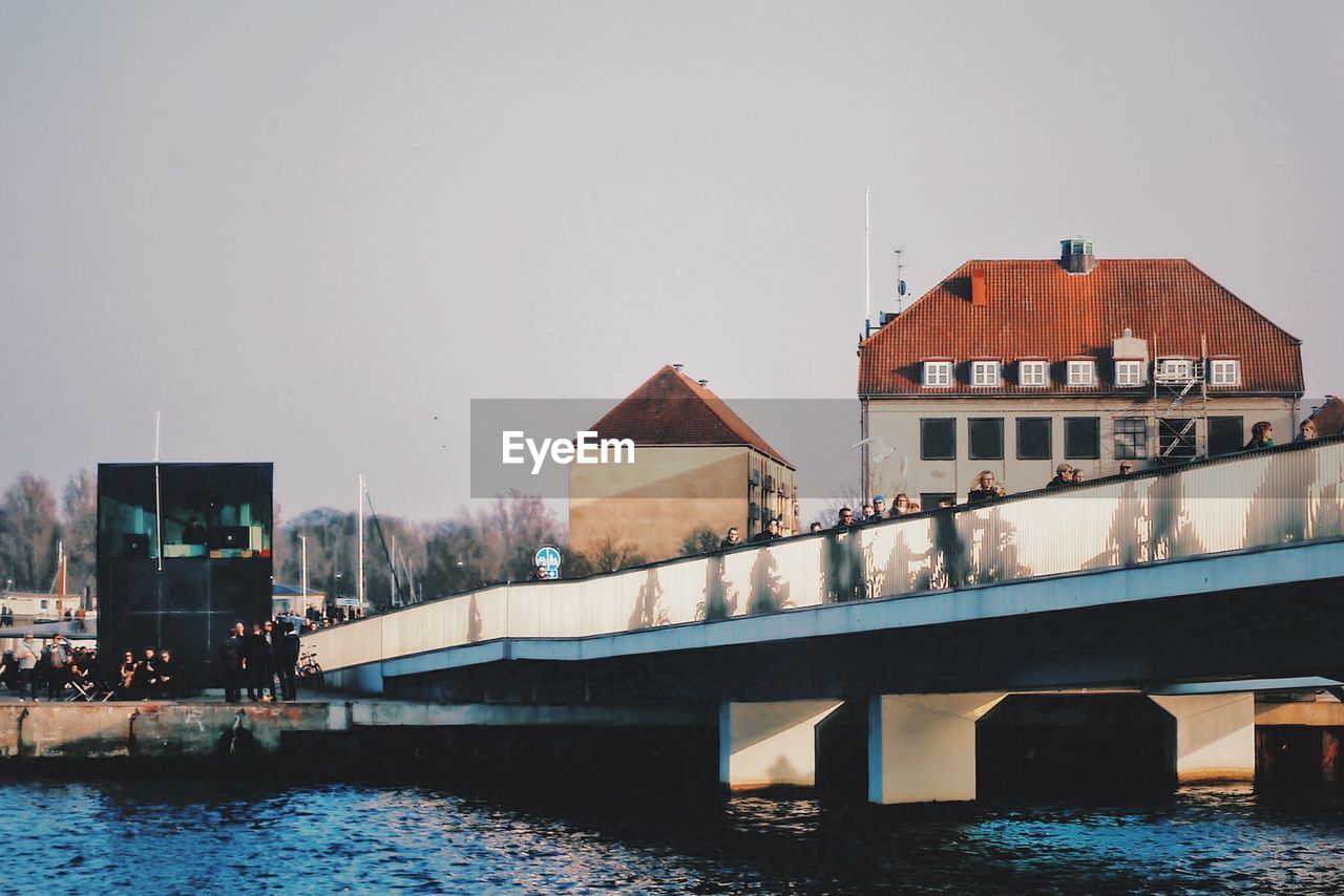 BUILDINGS BY RIVER AGAINST SKY IN CITY