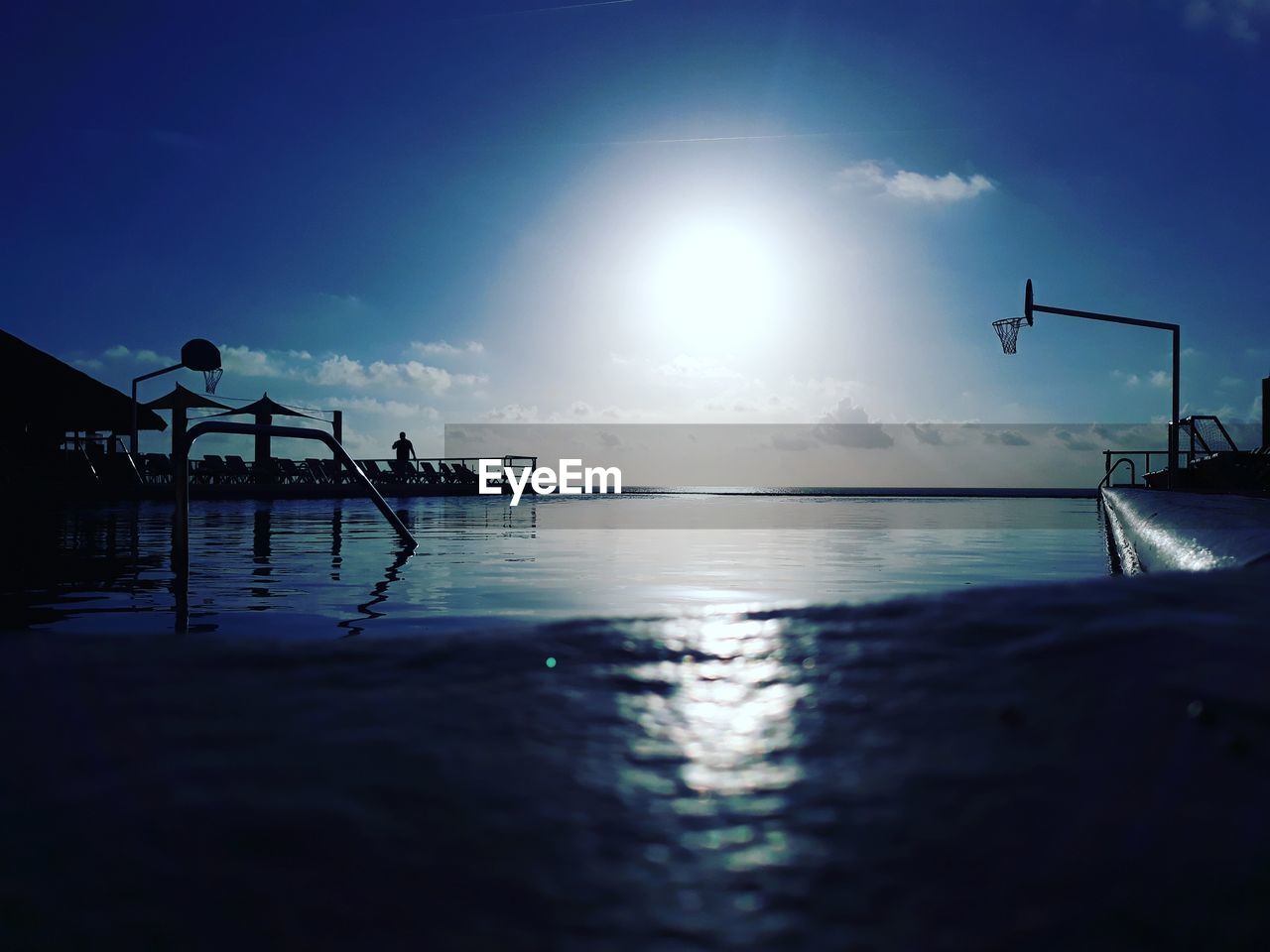 SILHOUETTE OF SWIMMING POOL IN SEA AGAINST SKY