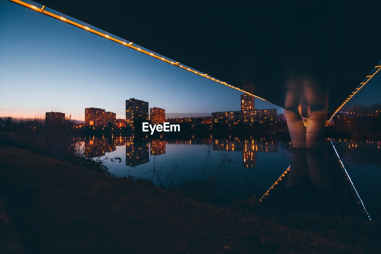 ILLUMINATED CITY BY RIVER AGAINST SKY