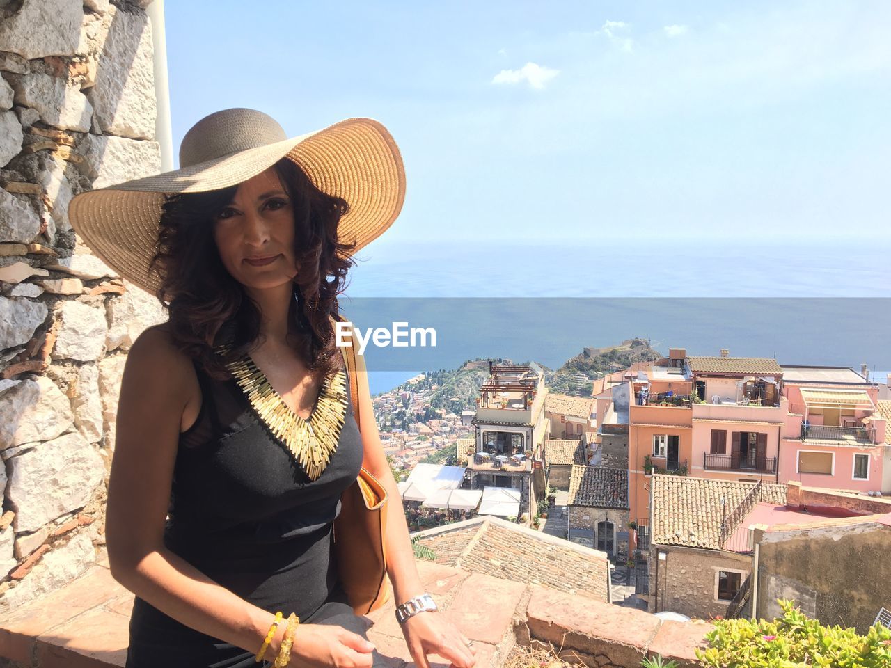 Portrait of woman in hat standing against sea