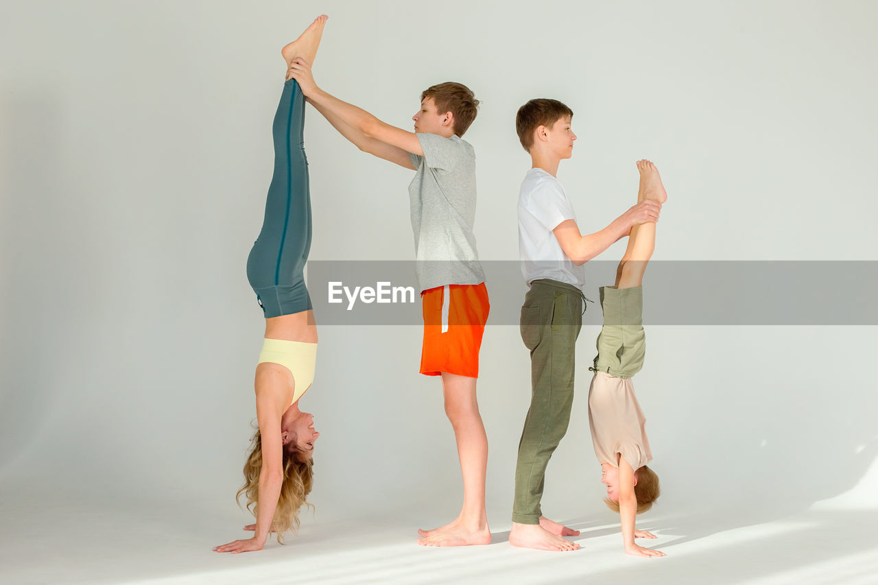 A sports family, a slender woman, a boy and two teenagers stand on their hands