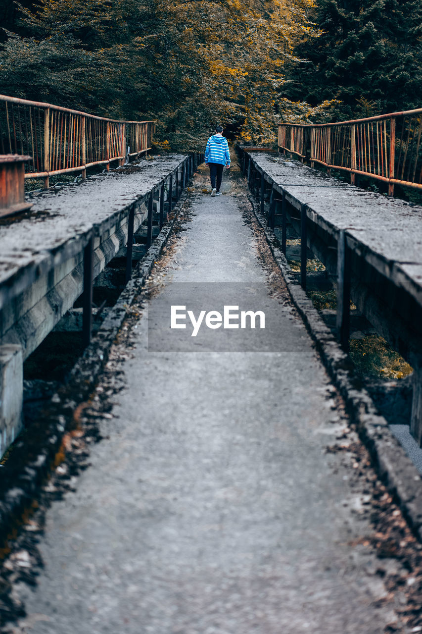 Rear view of man walking on footbridge