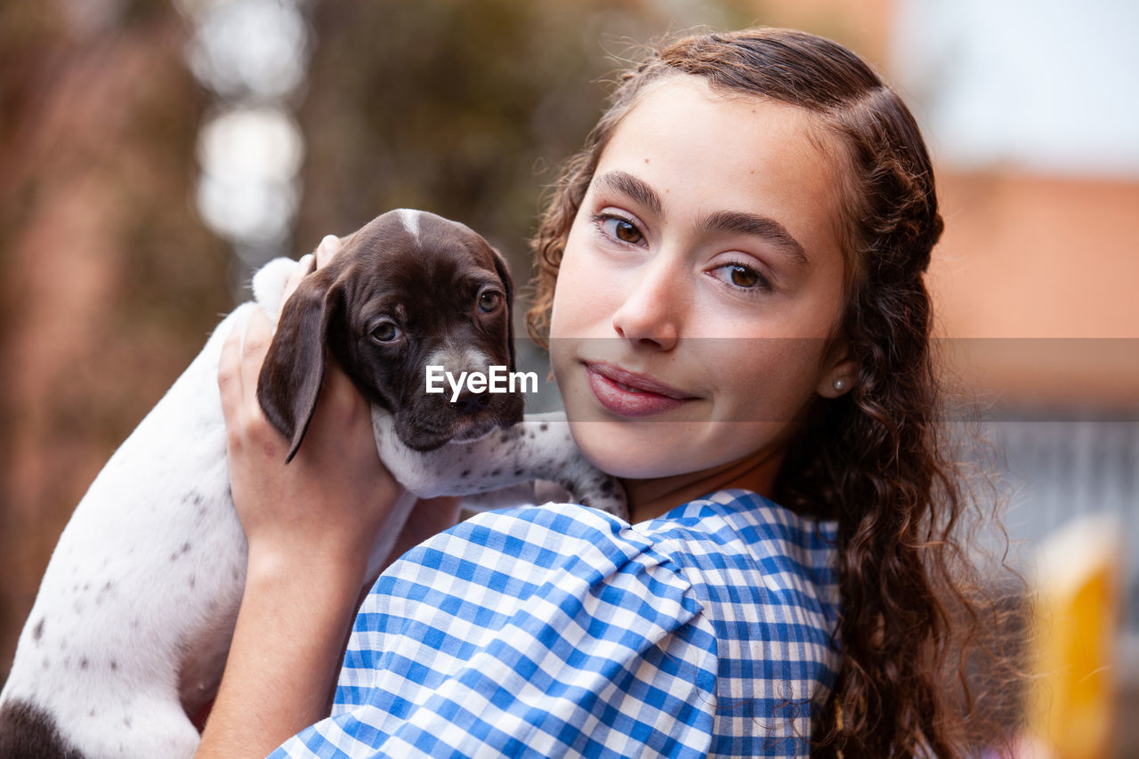 Beautiful young girl having fun with her small french braque puppy