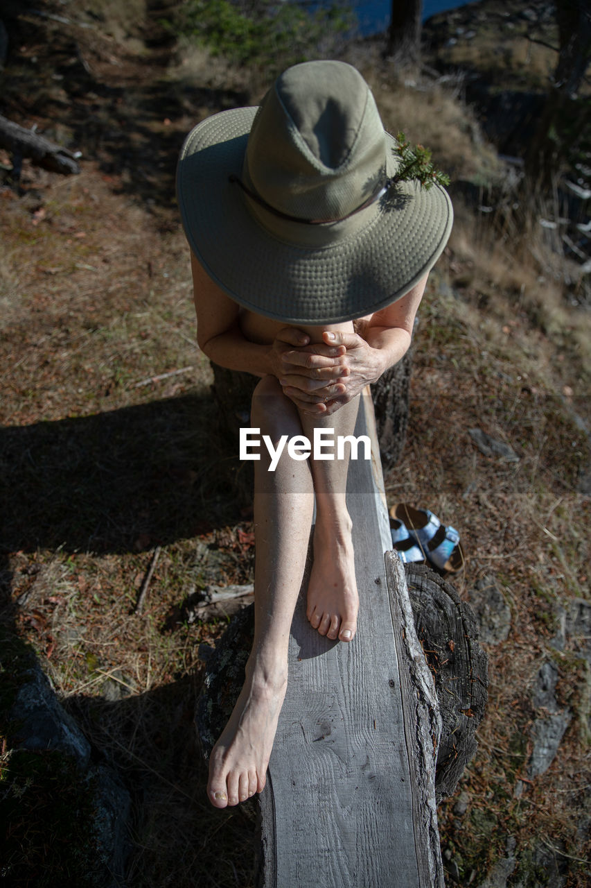 Woman wearing hat while sitting on wood