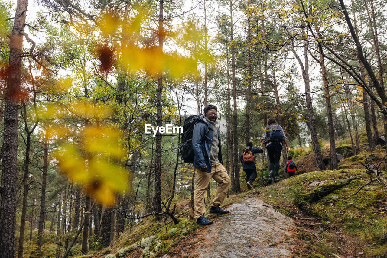 Side view of smiling man standing on trail in forest