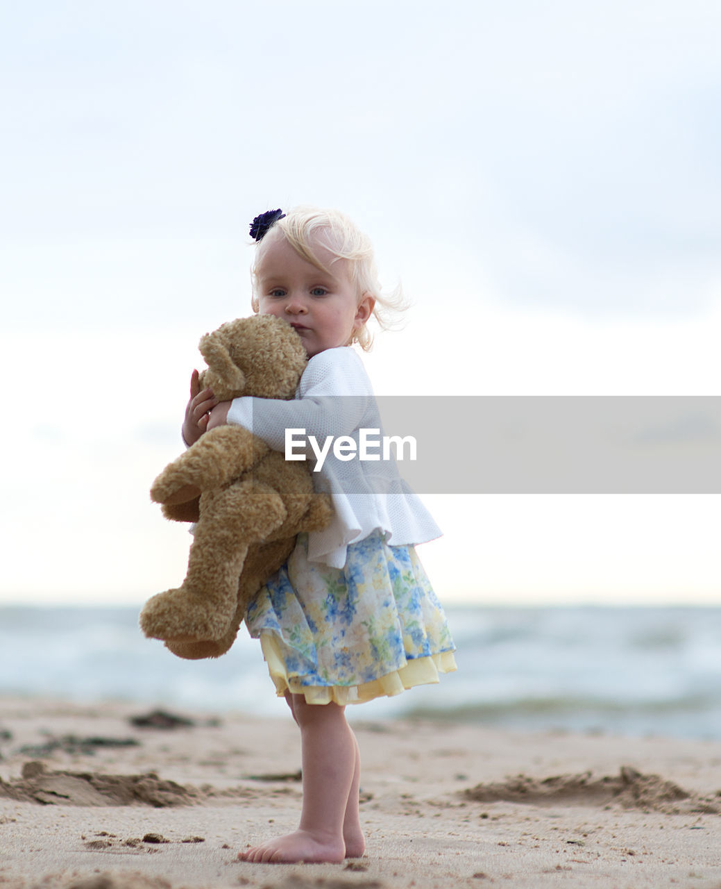Full length portrait of baby girls with toy at beach against sky