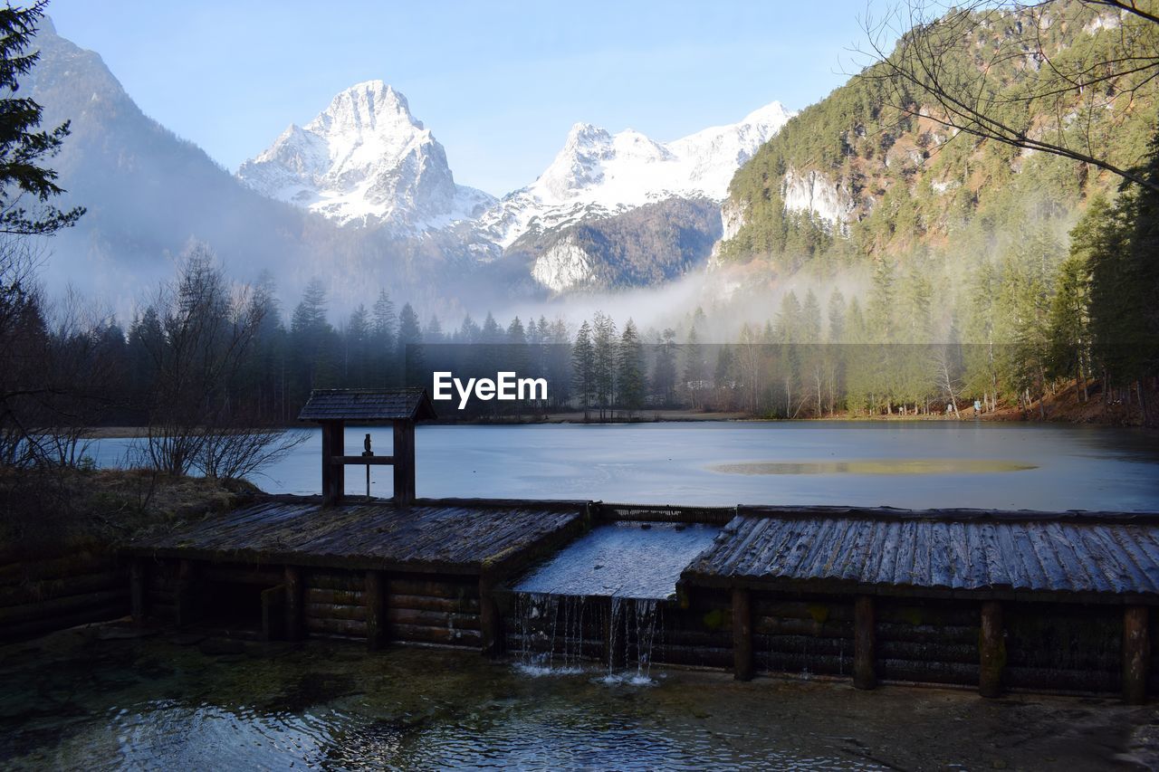Scenic view of lake by snowcapped mountains against sky
