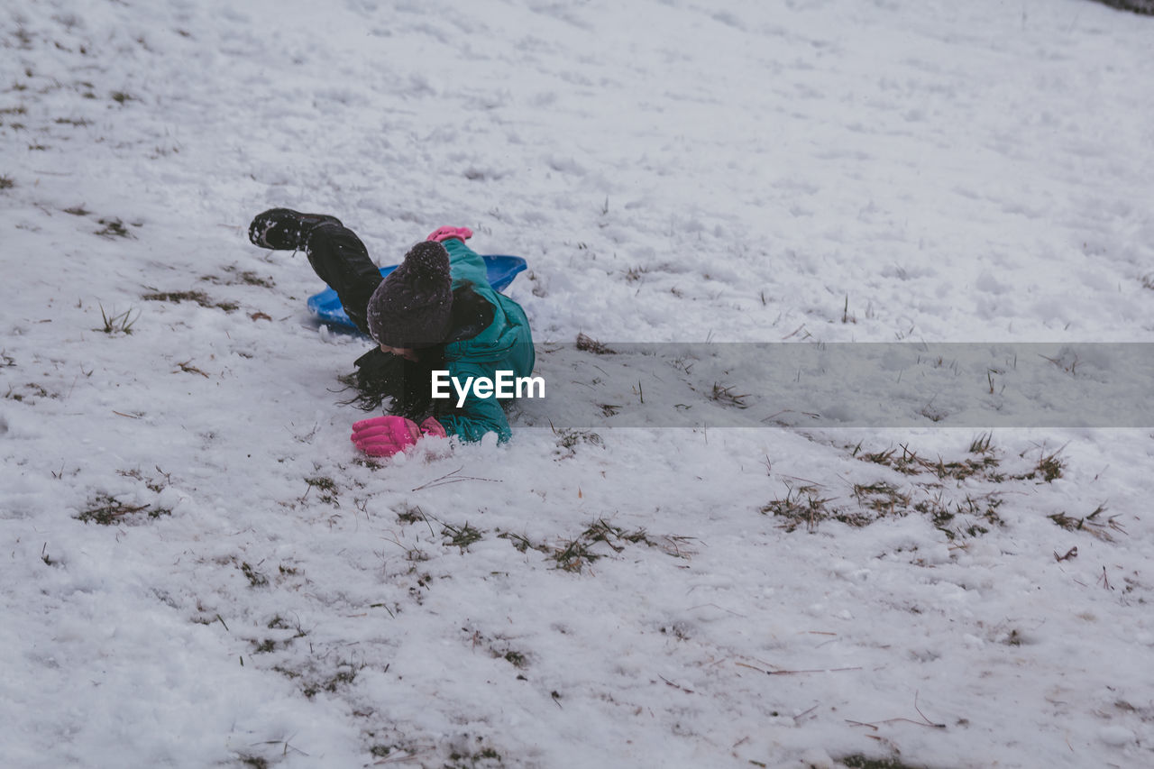 Full length of girl sitting on bobsled in snow