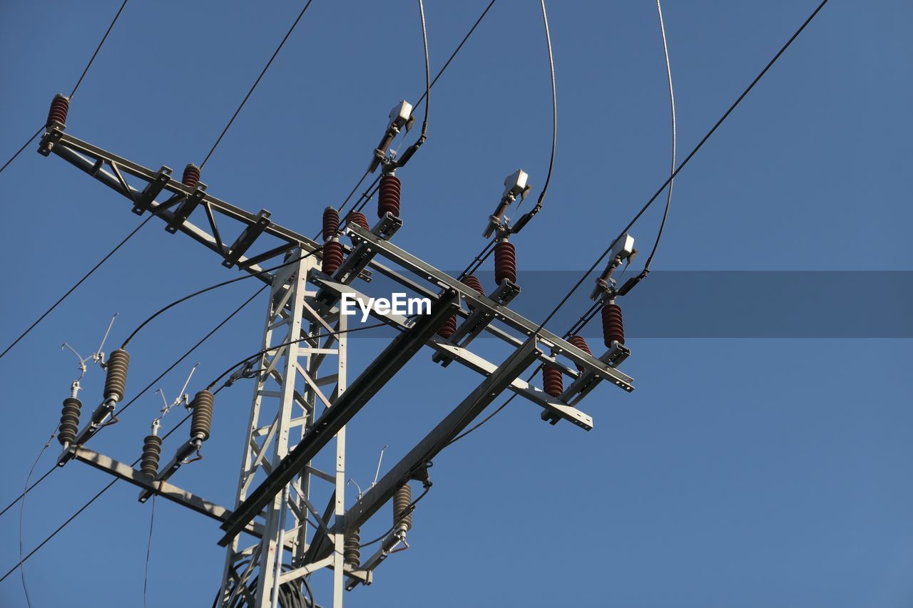 Low angle view of electricity pylon against clear sky