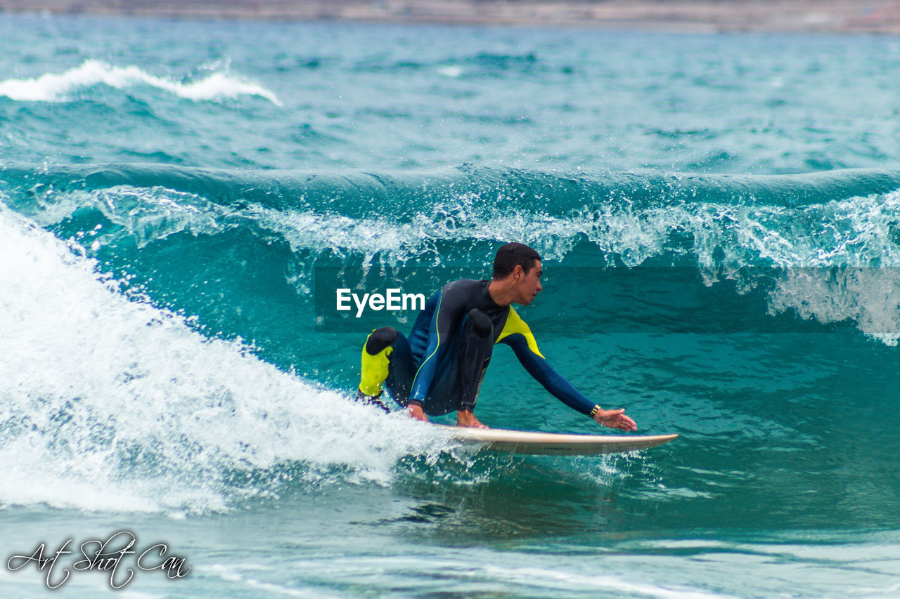 SIDE VIEW OF MAN SURFING ON SEA