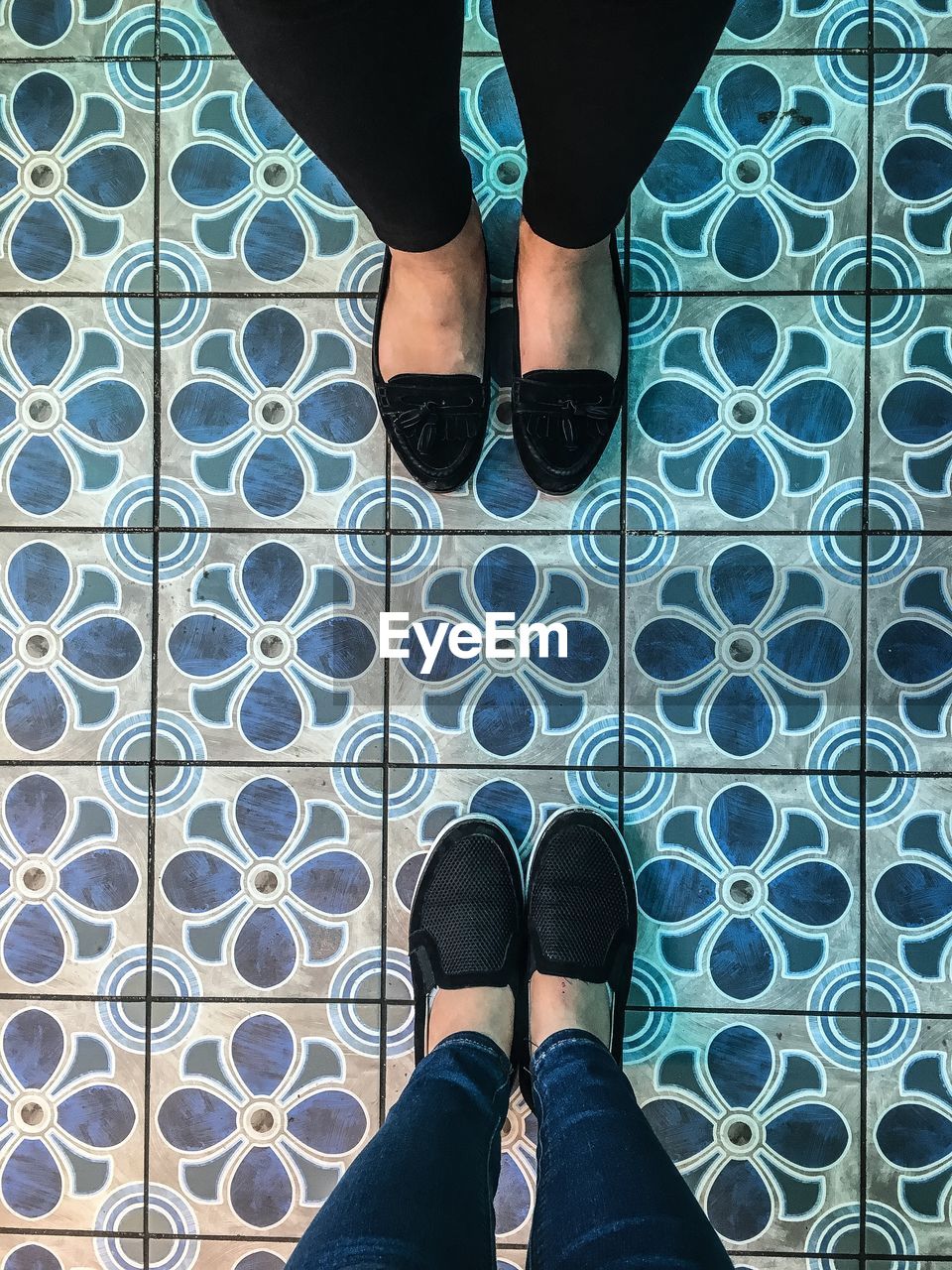 Low section of women standing on tiled floor