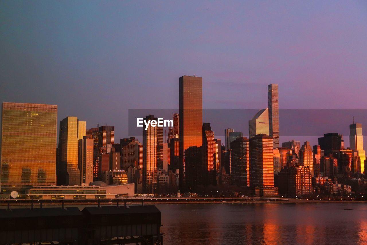 Modern buildings in city against sky during sunset