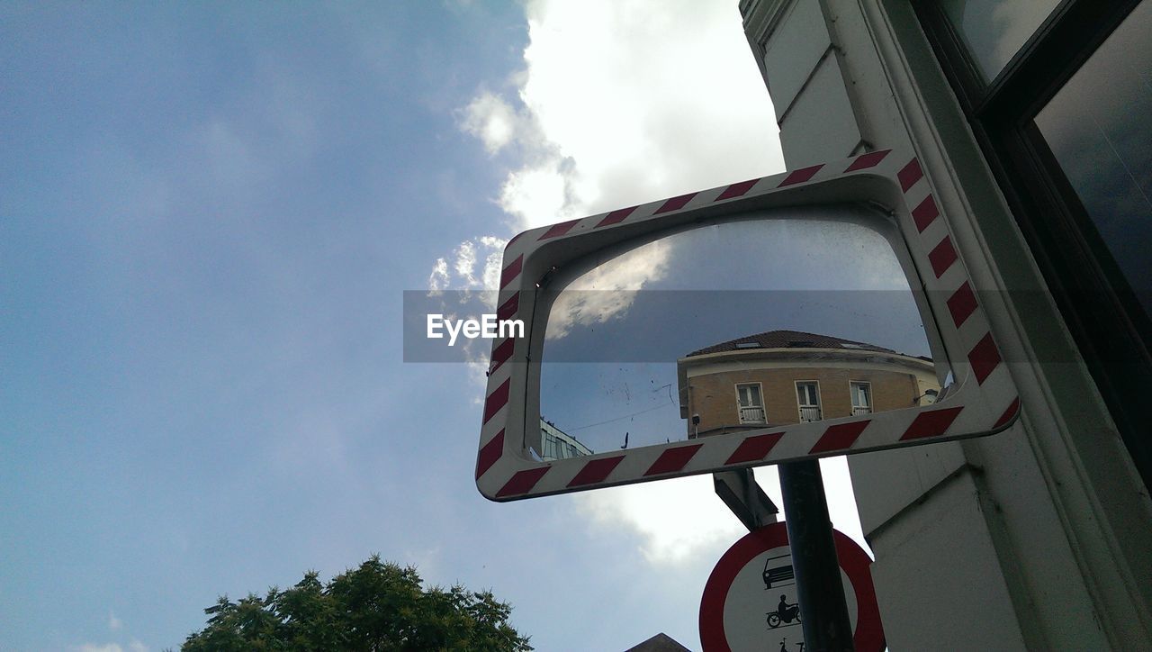 Low angle view of road mirror reflecting building