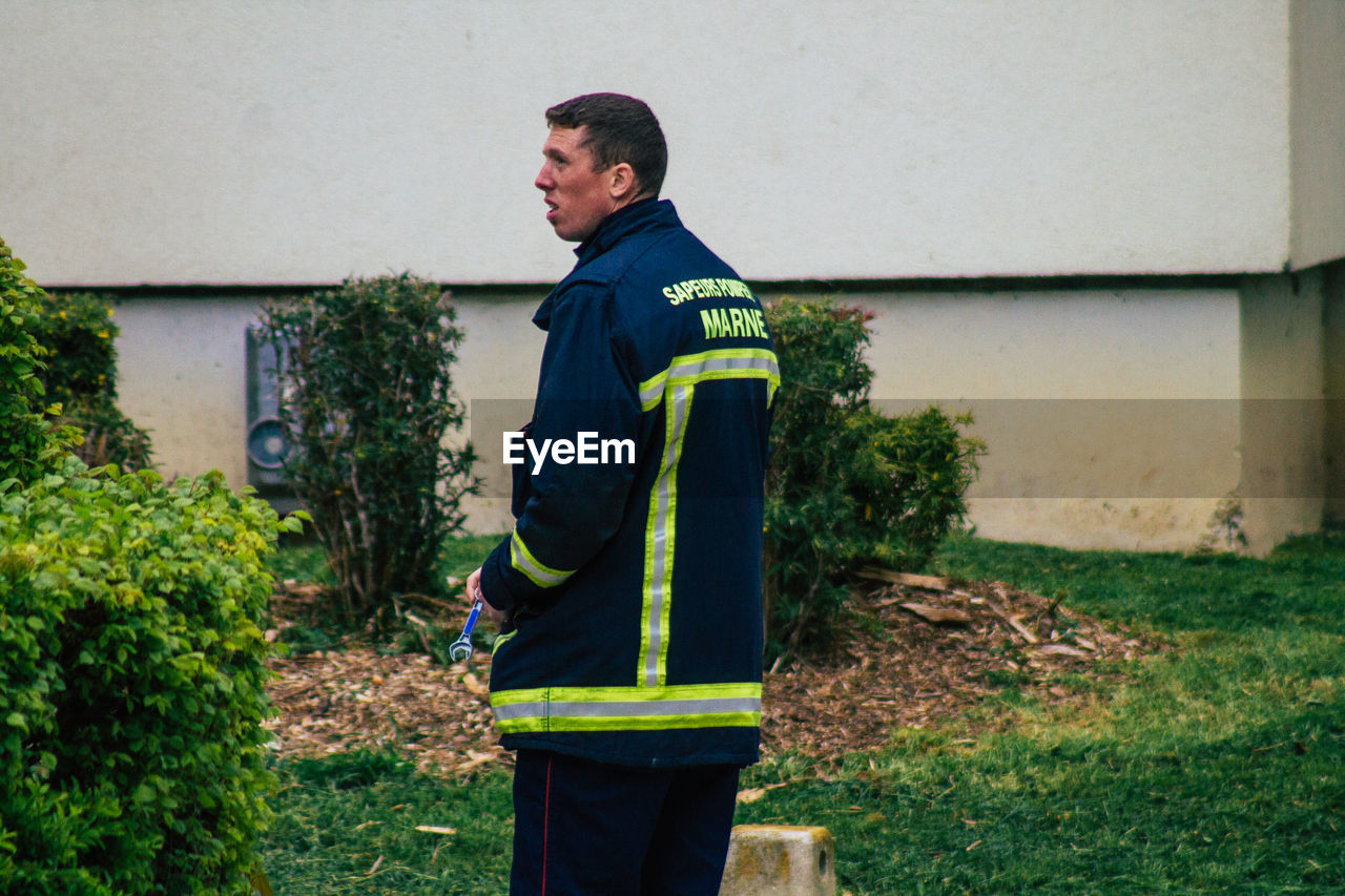 SIDE VIEW OF MAN STANDING BY PLANTS