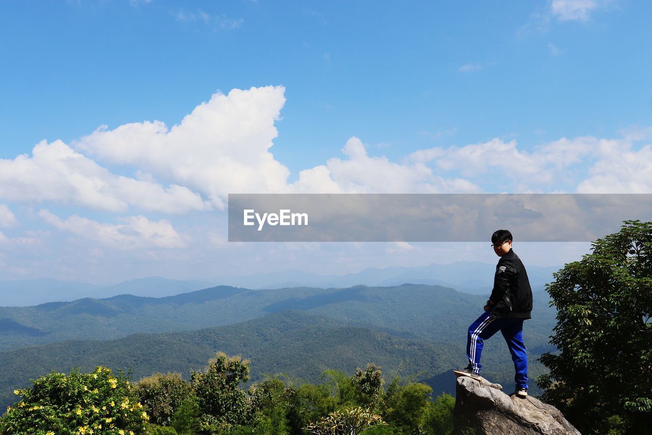 Man standing on rock against sky