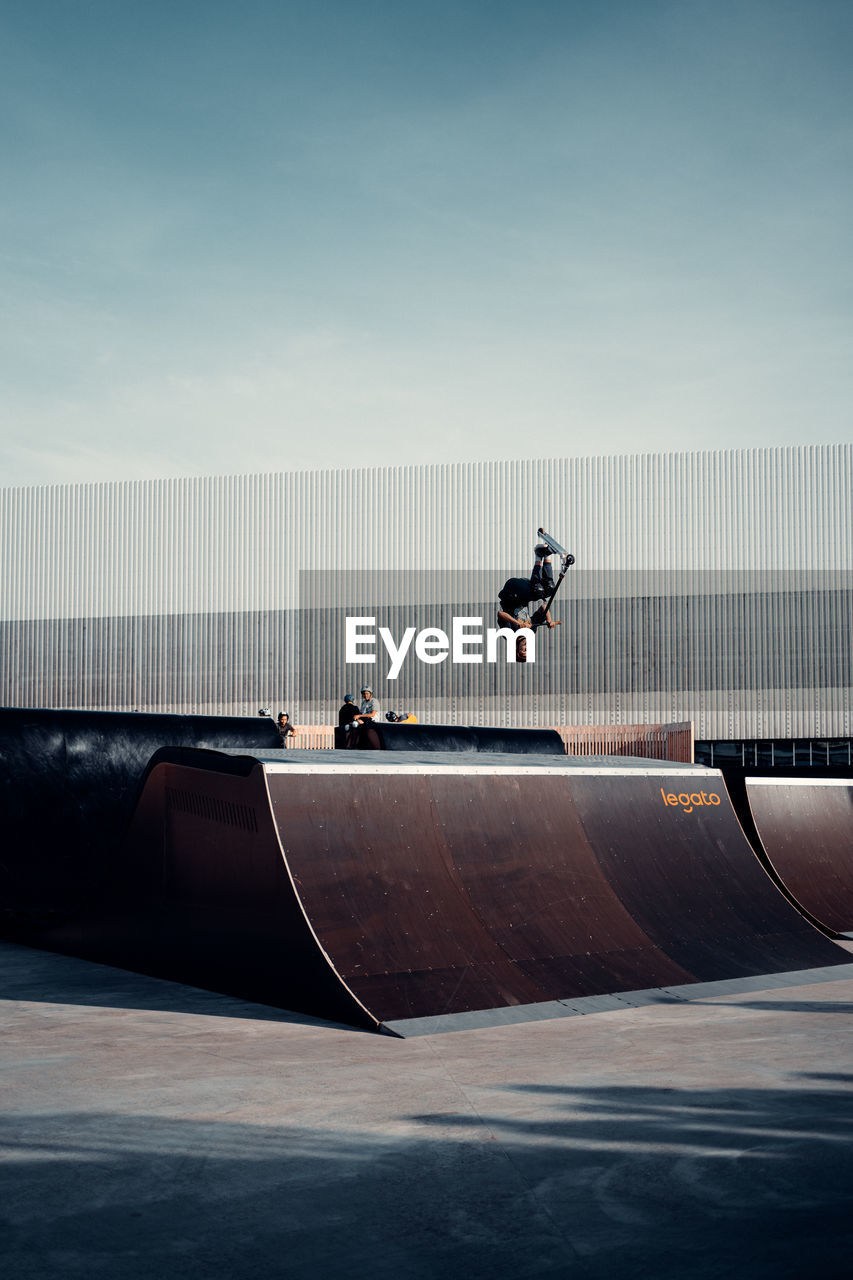 MAN SKATEBOARDING ON ROAD AGAINST SKY