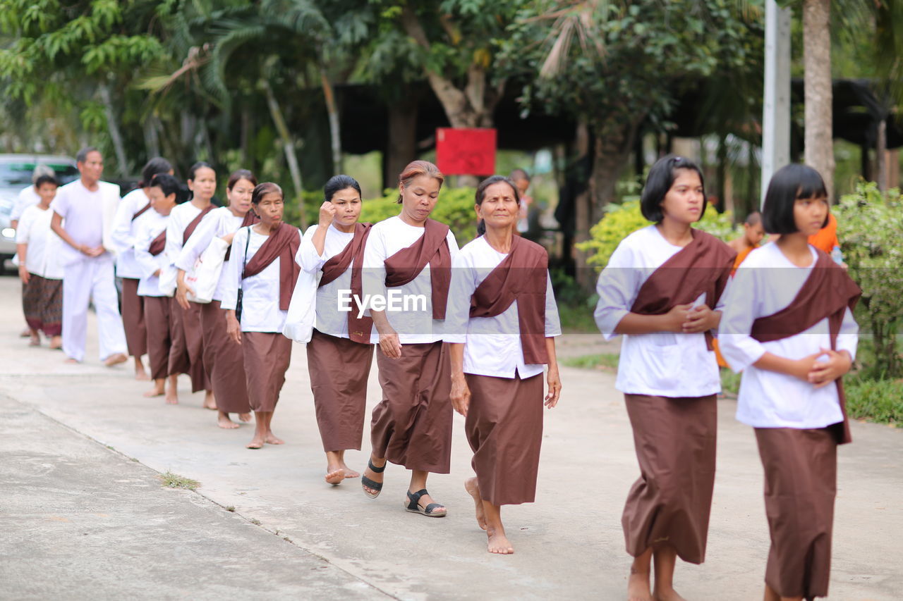 GROUP OF PEOPLE WALKING ALONG STREET