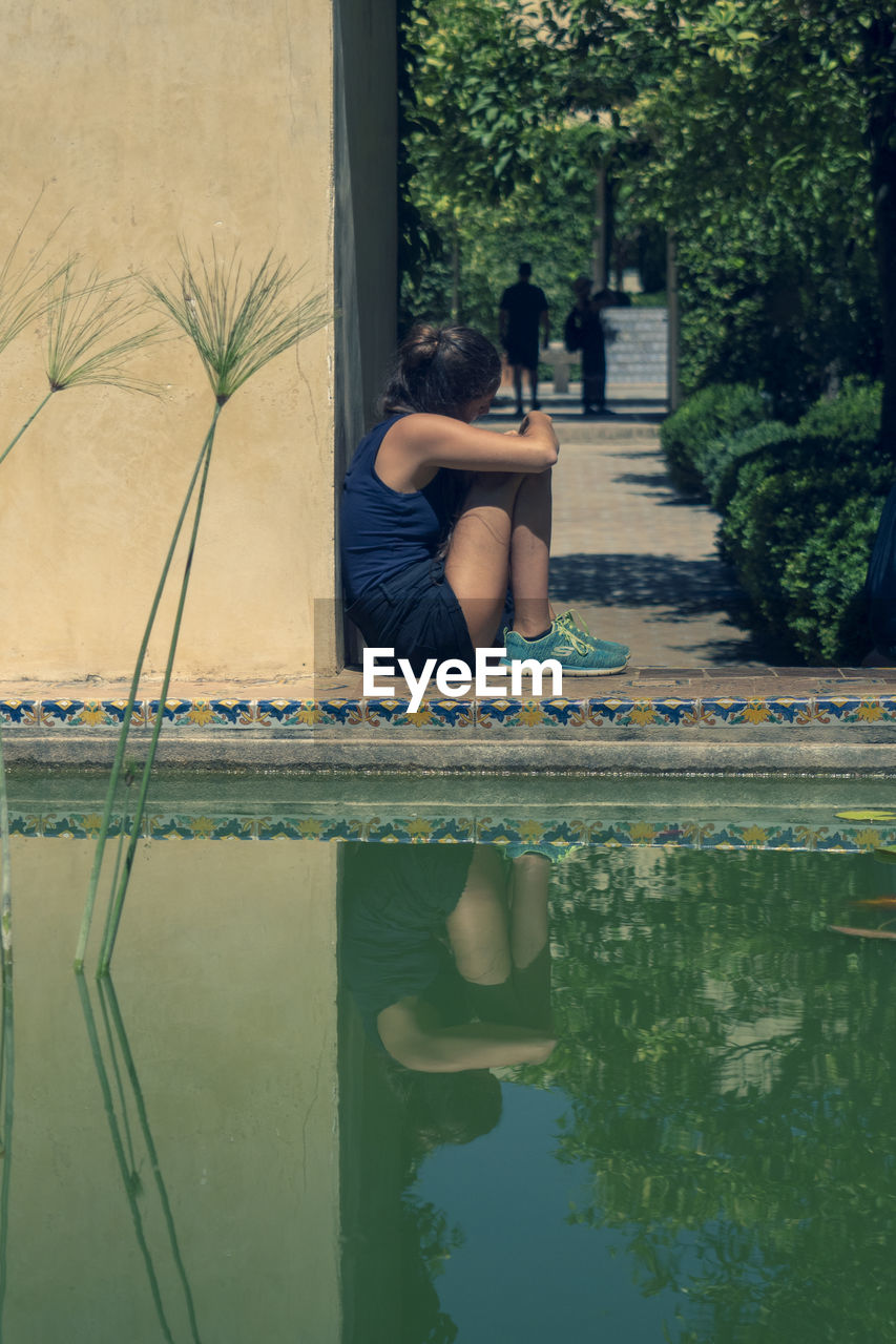 MAN SITTING BY SWIMMING POOL