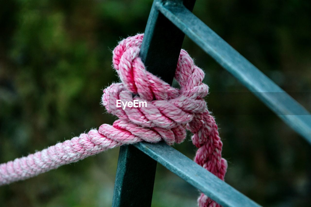 CLOSE-UP OF ROPE TIED UP ON PINK FABRIC